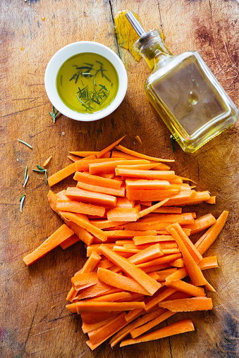 Carrot sticks, cut on a cutboard with a small bowl with  olive oil, ready to be prepared as typical italian \