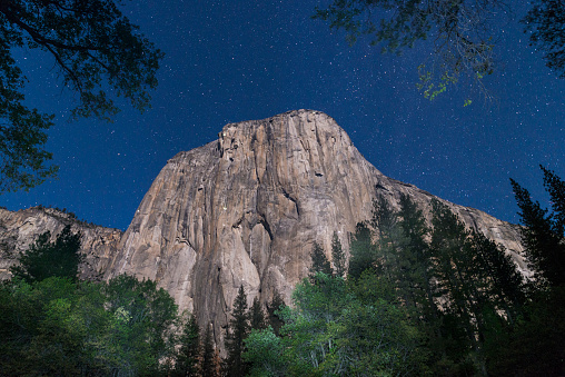 El Capitain mountain illuminated at night on a long exposure with multiple climbers camping on the rock side. Milky Way starry night