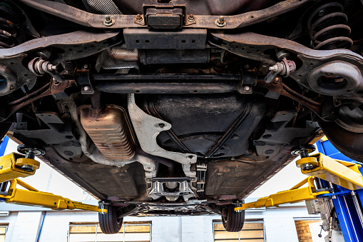 View of car undercarriage when lifted on hydraulic lift in a workshop during inspection