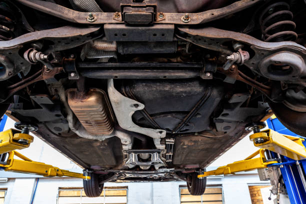 View of car undercarriage when lifted on hydraulic lift in a workshop during inspection View of car undercarriage when lifted on hydraulic lift in a workshop during inspection chassis photos stock pictures, royalty-free photos & images