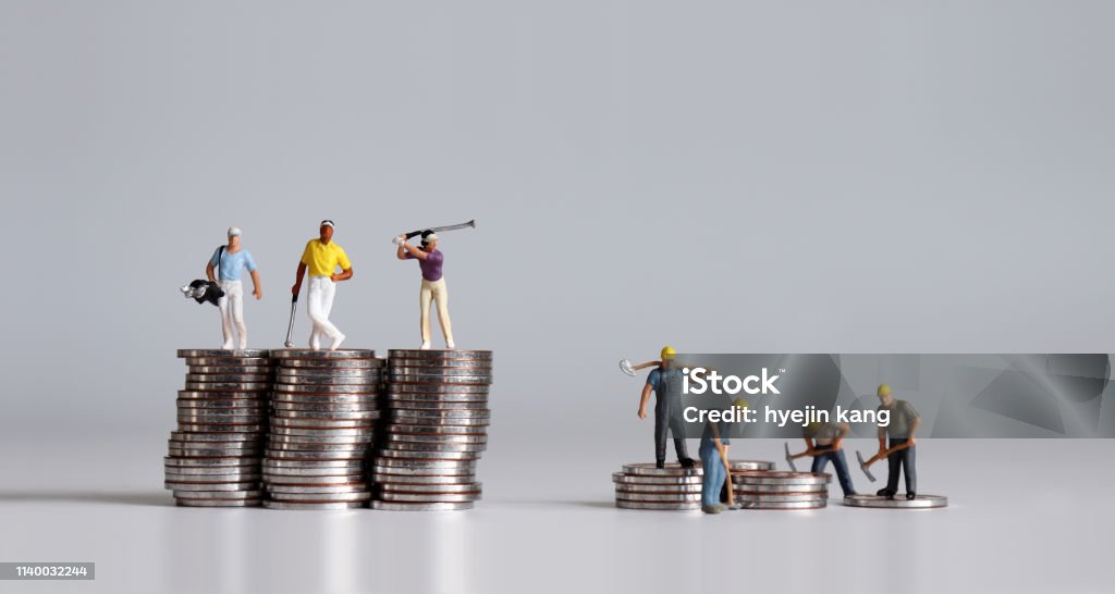 Miniature people standing on a pile of coins. A concept of income disparity. Imbalance Stock Photo