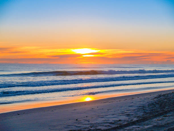 istock Wide beach image as sun rises above clouds on horizon 1140036597