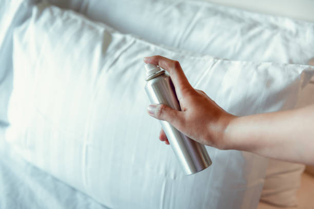 woman hand sta spruzzando deodorante per l'aria nel cuscino in camera da letto, odore sgradevole e concetto di aromaterapia - air freshener foto e immagini stock