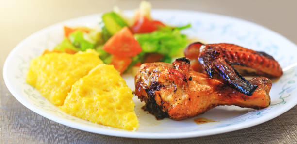 Baked chicken legs, Polenta or Mamaliga and salad in fancy plate. Traditional food and culinary culture specific for Balkan countries like Romania, Moldova and Ukraine. Baked chicken legs, Polenta or Mamaliga and salad in fancy plate. Traditional food and culinary culture specific for Balkan countries like Romania, Moldova and Ukraine. Conceptual picture for healthy dinner. mamaliga stock pictures, royalty-free photos & images