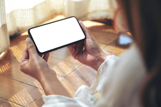istock a woman holding and using black mobile phone with blank desktop screen while laying down on the floor 1140066385