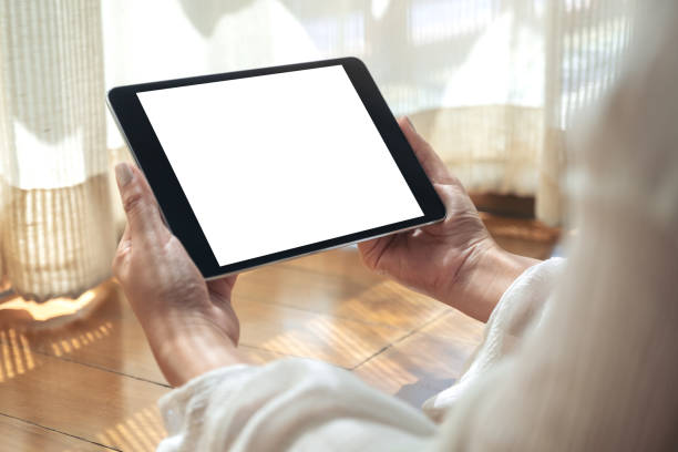 istock a woman holding black tablet pc with blank white desktop screen horizontally while laying down on the floor 1140066969