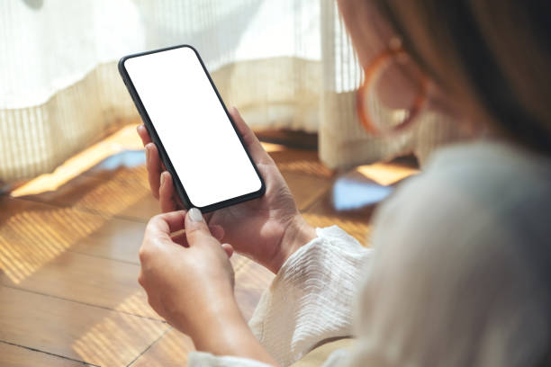 istock a woman holding and using black mobile phone with blank desktop screen while laying down on the floor 1140067039