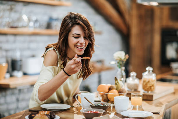 Happy woman eating marmalade in the kitchen.