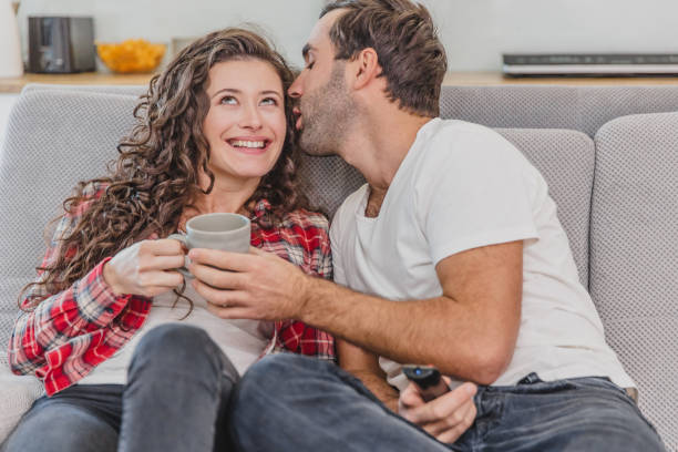 istock Beautiful hilarious young man holding a remote control. During this, she watches a whirlwind and kisses her cheek. Put two on the couch at home. 1140067232