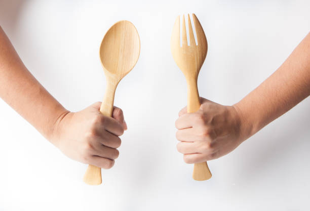 istock Hand holder wooden spoon and fork, white background. Wooden kitchenware 1140067282