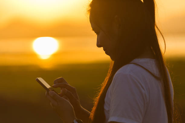 istock Asian woman using smartphone at sunset 1140067599