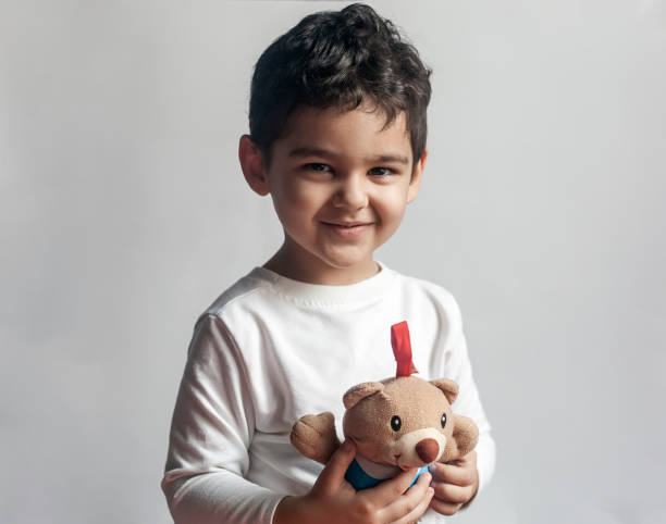5 years adorable little kid boy playing with plush bear toy stock photo