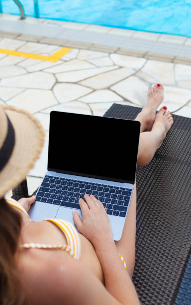 istock Young woman using laptop near a swimming pool 1140072195