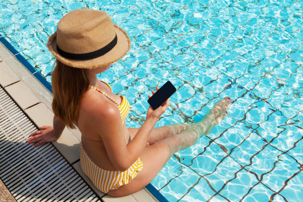 istock Young woman using smartphone near a swimming pool 1140072342