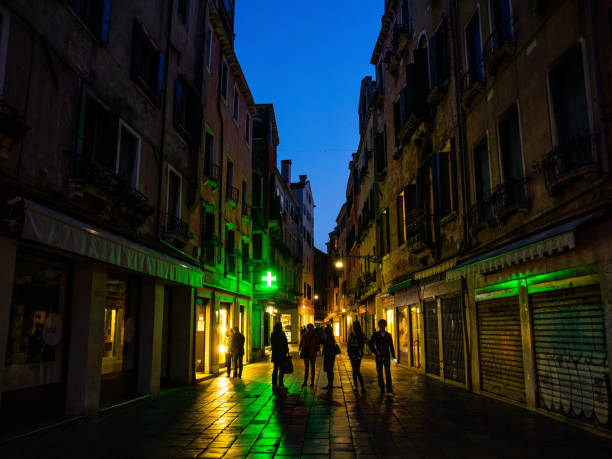 Venice, Italy - April 6 2016: The street in Venice old town just after the sunset. The street is decorated by neon signs and the right is reflected on the stony floor on the street.