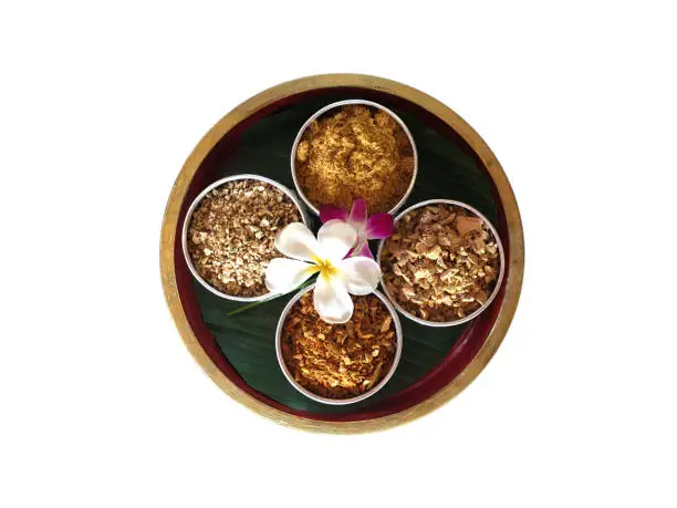 Photo of Mix dry herb for herbal ball inside silver cup on wooden bowl isolated on white background.