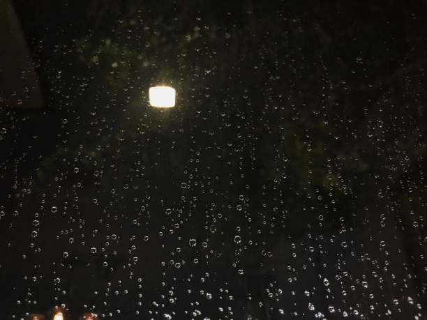 istock Raindrops on blur window in the night behind lighting lamp effect. Translucent like mist on the glass from rainy at night temperature. 1140074045