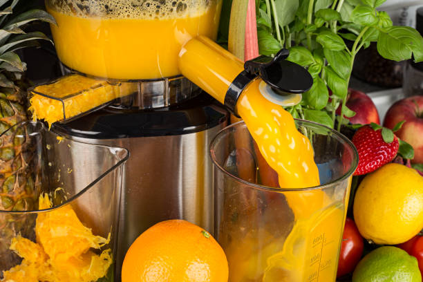 慢榨汁機在廚房與許多水果和蔬菜橙汁健康生活方式的概念背景 - 榨汁機 個照片及圖片檔