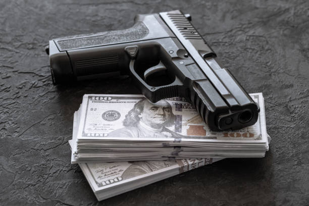 istock Pistol and money. Guns and dollars on black background 1140075295