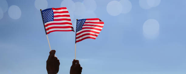istock hands of two couple holding American flag 1140075689