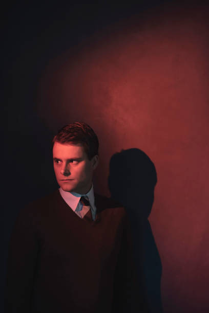 istock Man in white shirt and brown sweater in red light. 1140077900
