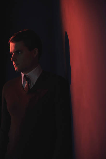 istock Man in white shirt and brown sweater in red light. 1140077904
