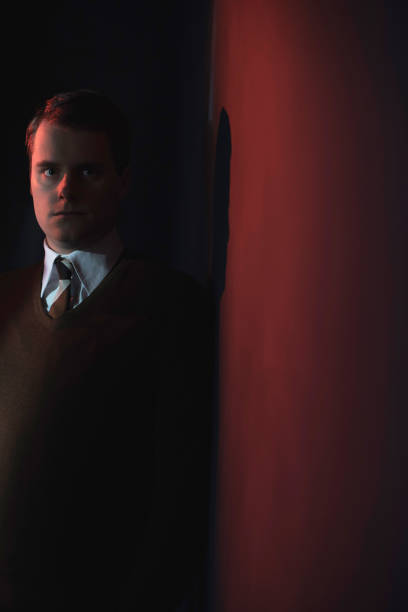 istock Man in white shirt and brown sweater in red light. 1140077912
