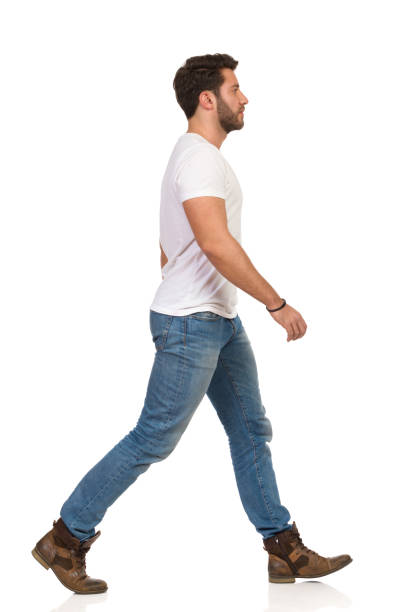 istock Seriois Young Man In Jeans And White T-shirt Is Walking. Side View 1140078274