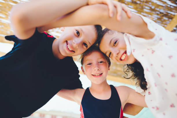 Two girls and a boy in a line embracing, isolated on white background