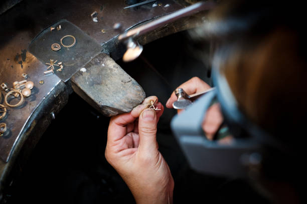 bijoutier scies à une bague en or dans l’atelier de bijoux authentique - diamond jeweller jewelry examining photos et images de collection