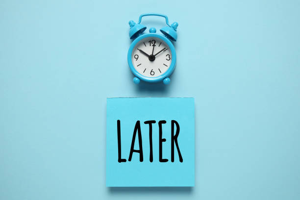 istock Blue alarm clock and paper reminder, later. Time management, priorities, efficiency, control and goals 1140085376