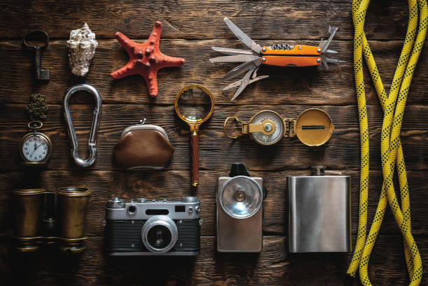 Travel. Tourist. Travel or adventure equipment and accessories abstract flat lay background. Photo camera, flashlight, multitool knife, rope, carbines, binoculars, compass, wallet, key, loupe and a starfish on table. wallet gun stock pictures, royalty-free photos & images