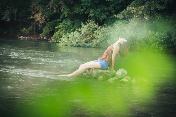 istock Girl sitting on a stone in the river 1140086849