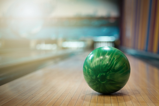 Green bowling ball on an alley background.