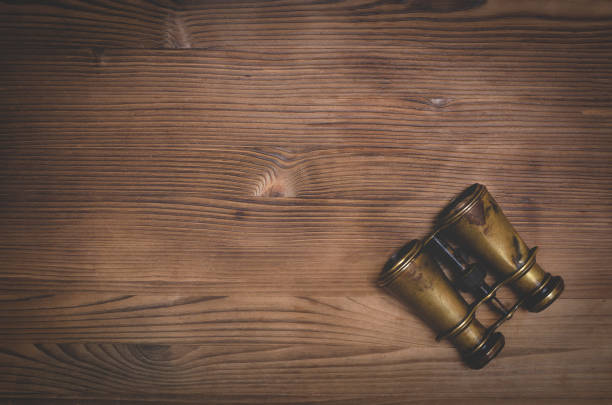 Travel or adventure flat lay background with copy space. Binoculars on a brown wooden table.