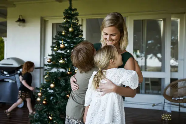 Cropped shot of a loving mother embracing her two kids on Christmas morning