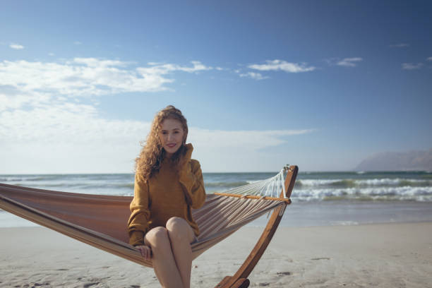 istock Woman looking at camera sitting on hammock at beach 1140095809