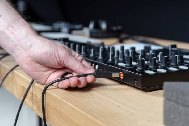 istock Man connects DJ instruments to the network for create electronic music inside in black modern and sound studio with wooden table and style interior 1140095933