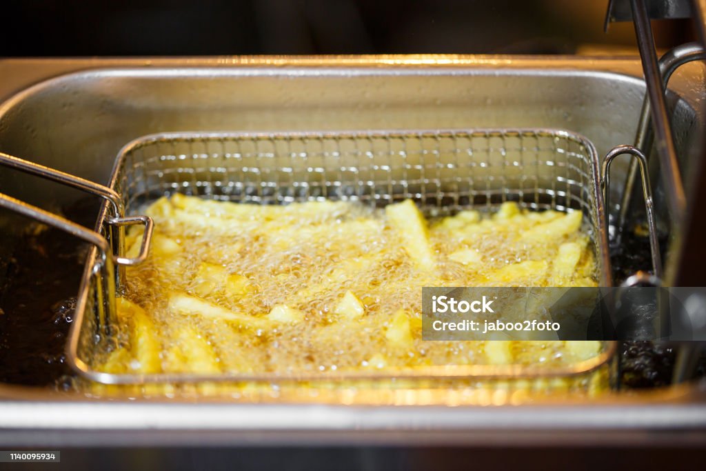 close up French Fries Potatoes cooking in basket of Frying Machine , deep fried in Hot Boiling Oil Close-up Stock Photo