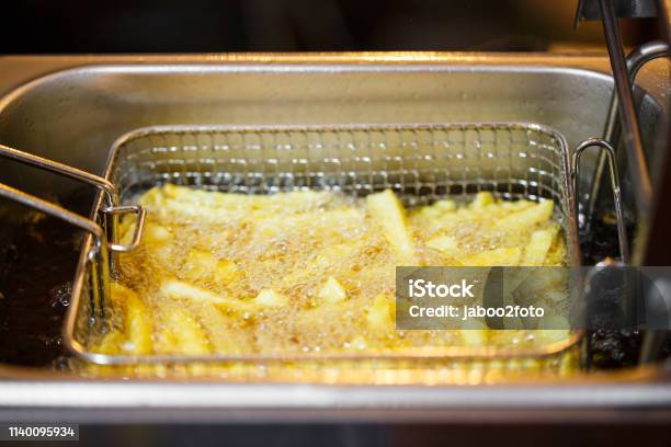 Close Up French Fries Potatoes Cooking In Basket Of Frying Machine Deep Fried In Hot Boiling Oil Stock Photo - Download Image Now