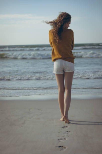 istock Woman walking on sand at beach 1140096091