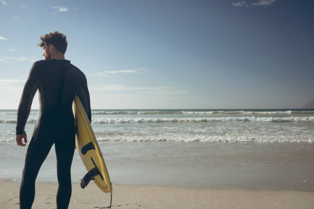 istock Male surfer with a surfboard standing on a beach 1140096201