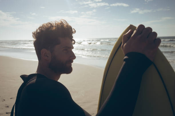 istock Male surfer with a surfboard standing on a beach 1140096240