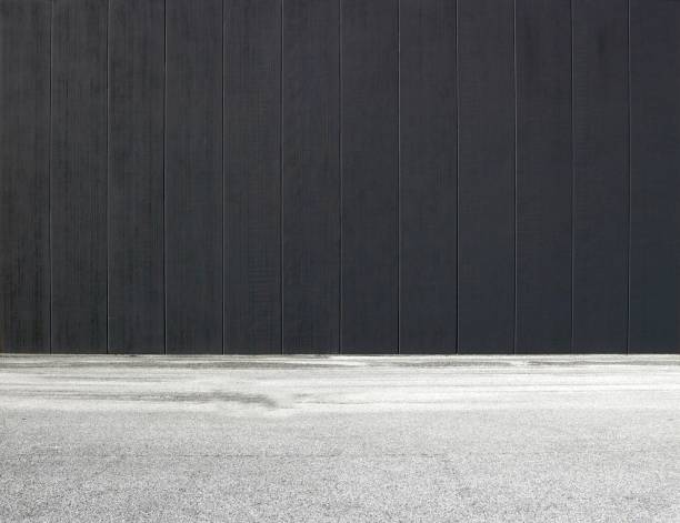 istock Black concrete wall with vertical stripes and an asphalt road in front. Background for copy space 1140096292