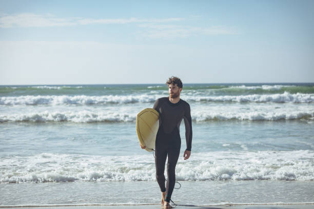 istock Male surfer with a surfboard walking on a beach 1140096309
