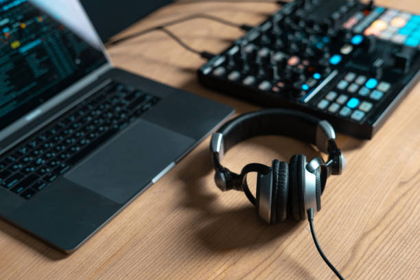 istock Laptop, DJ controller and headset lying on wooden table in sound studio with trendy black modern interior 1140096874