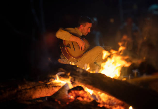 junger mann spielt akustische gitarre durch das feuer - men artist guitarist guitar stock-fotos und bilder