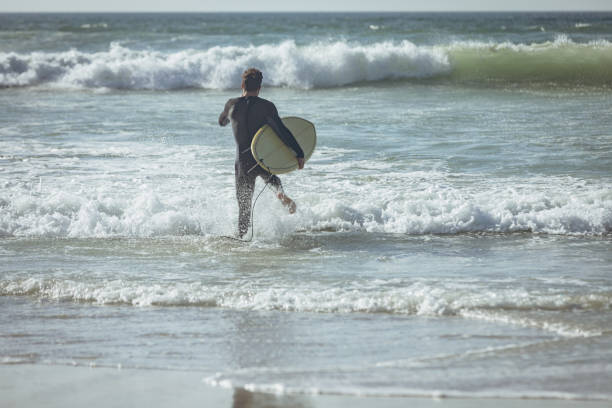 istock Male surfer with a surfboard running on a beach 1140097992