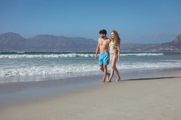 istock Couple walking with arm around at beach 1140098940