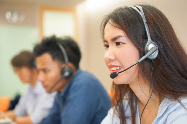 da vicino donna asiatica sorridente con gruppo di multietnici giovane dipendente agente call center indossare dispositivo auricolare che lavora con service-mind sul tavolo del pc desktop in sala operativa, telemarketing e concetto di help desk - pc desktop pc women desk foto e immagini stock